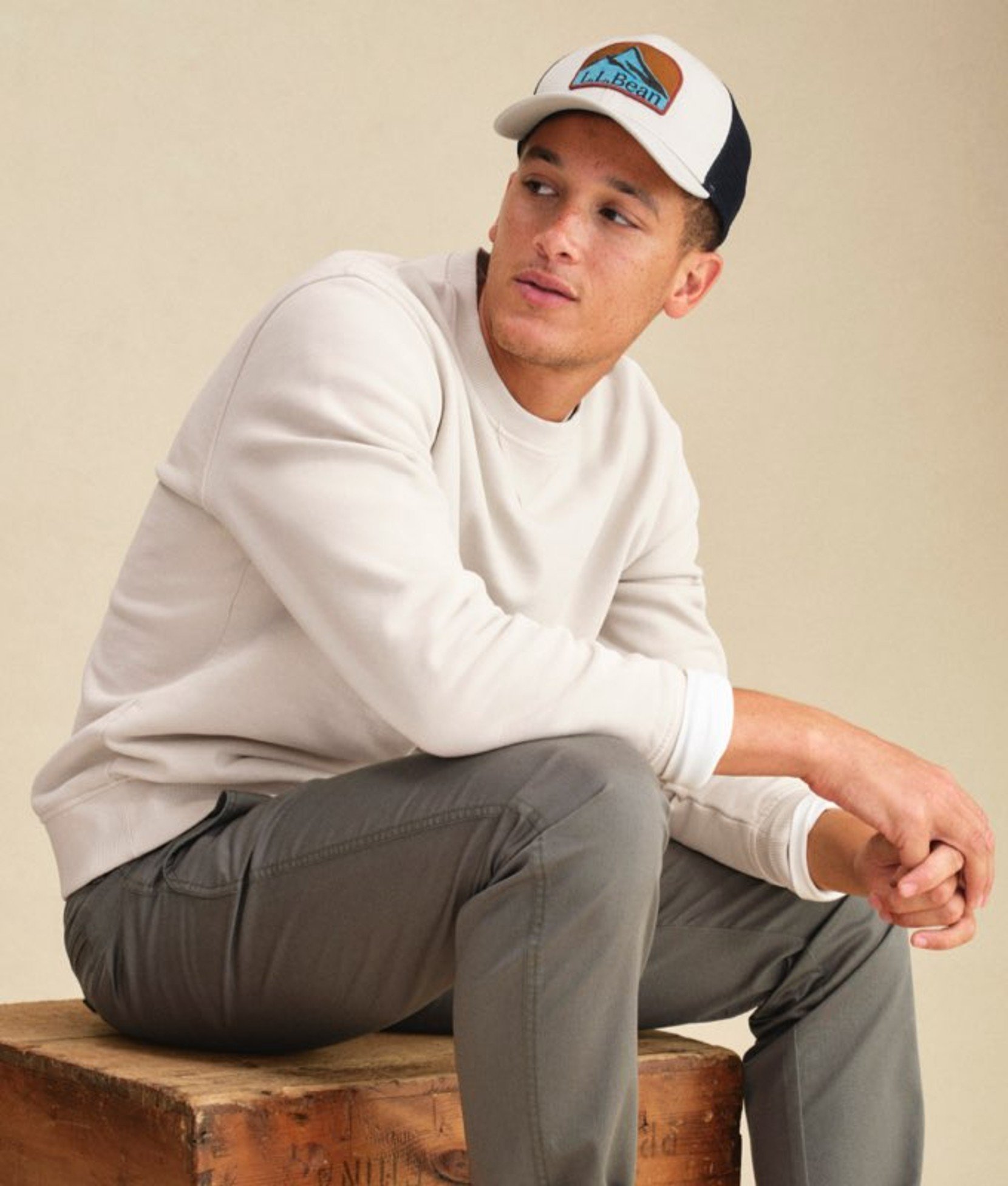 Man seated wearing a light gray sweatshirt and dark pants.
