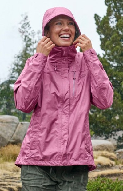 Person wearing a pink rain jacket with the hood up, standing outdoors in light rain.