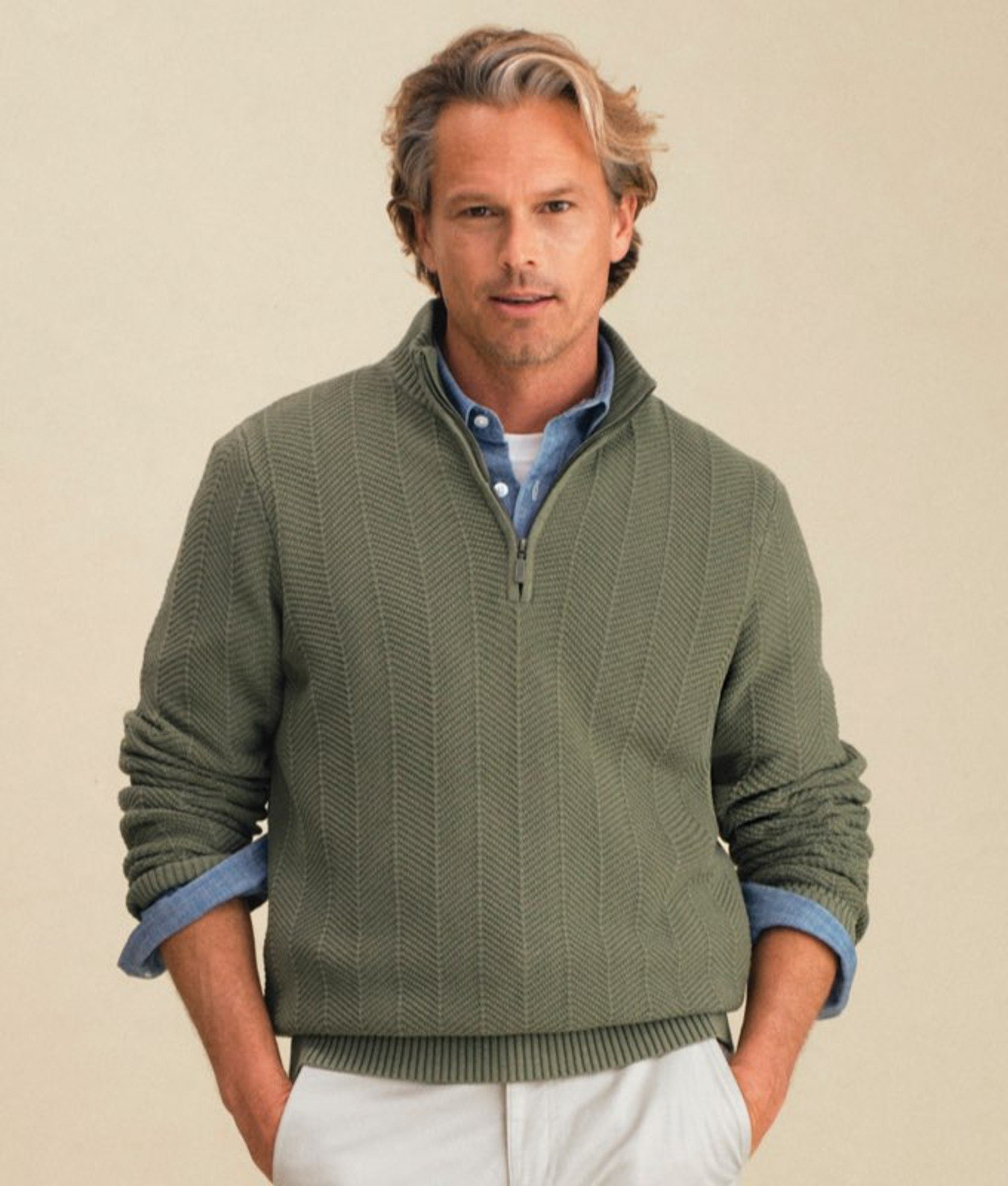 Man wearing a green sweater vest over a plaid button-down shirt.