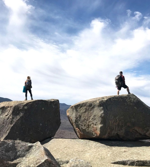 2 hikers atop separate boulders enjoying the view.