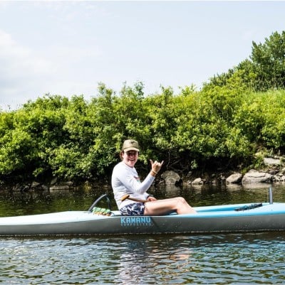 Woman in a kayak waving to the photographer.