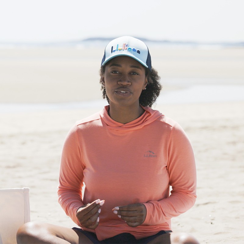 Stephanie, sitting on the sand wearing a SunSmart pullover.