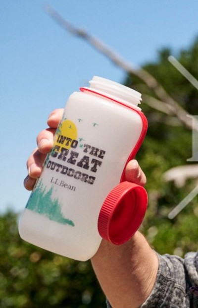 Hand holding a white water bottle with an outdoor themed illustration printed on the front and red screw-top lid.