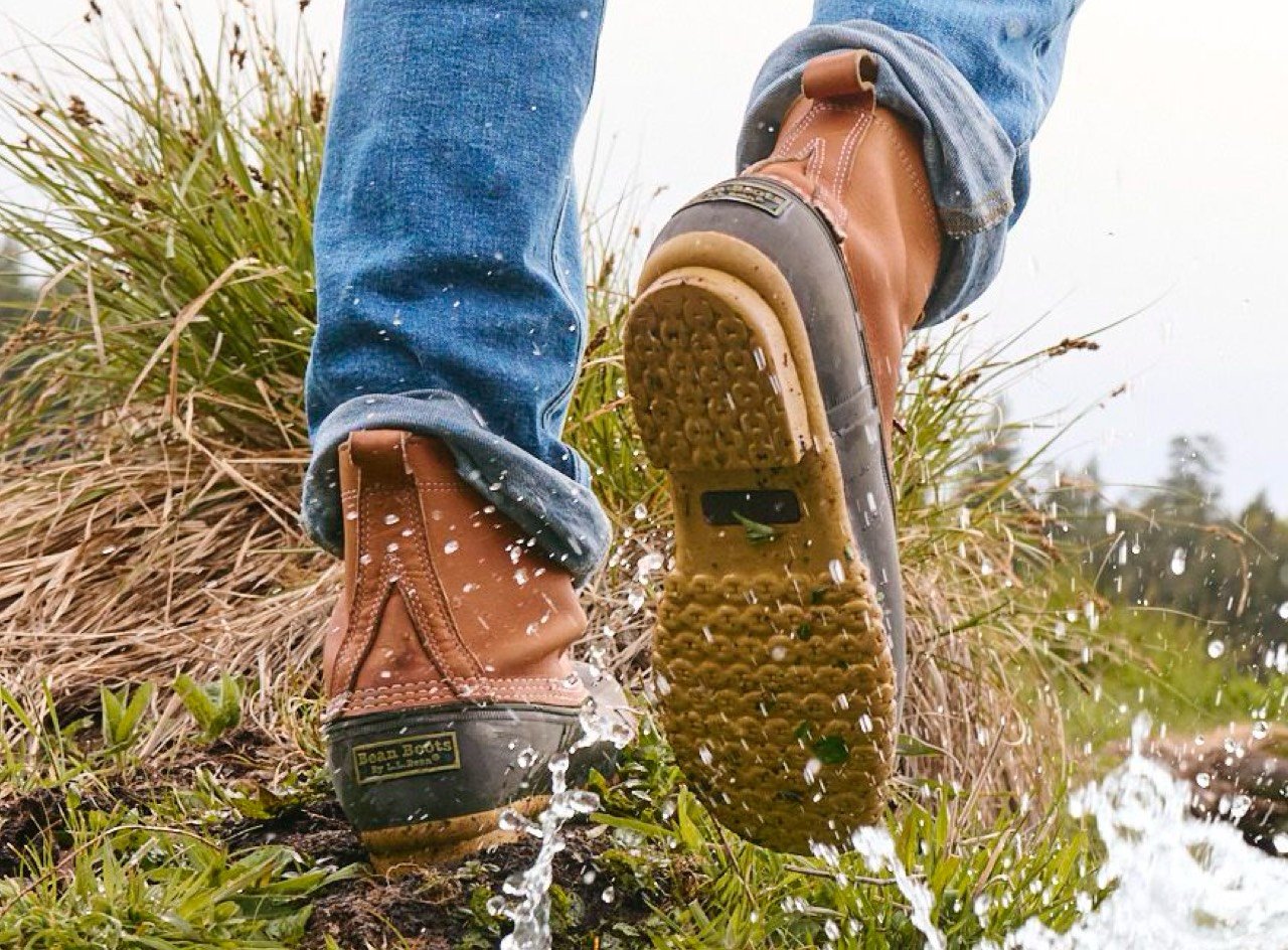 Man wearing L.L.Bean Boots walking in a marshy field.