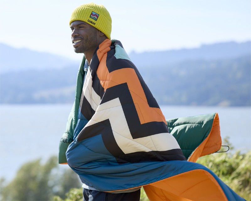 Man wearing outdoor blanket outside with a lake in the background