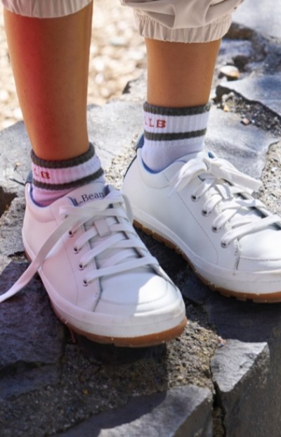 White L.L.Bean sneakers and gray-striped socks on a child standing on a rocky surface.