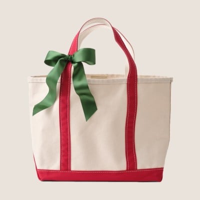 Canvas tote with red trim and green ribbon tied to one handle.