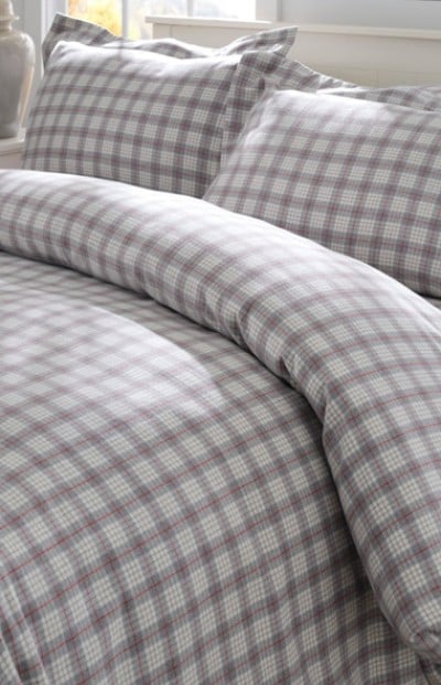 A neatly folded bed with matching plaid bedding and pillows.