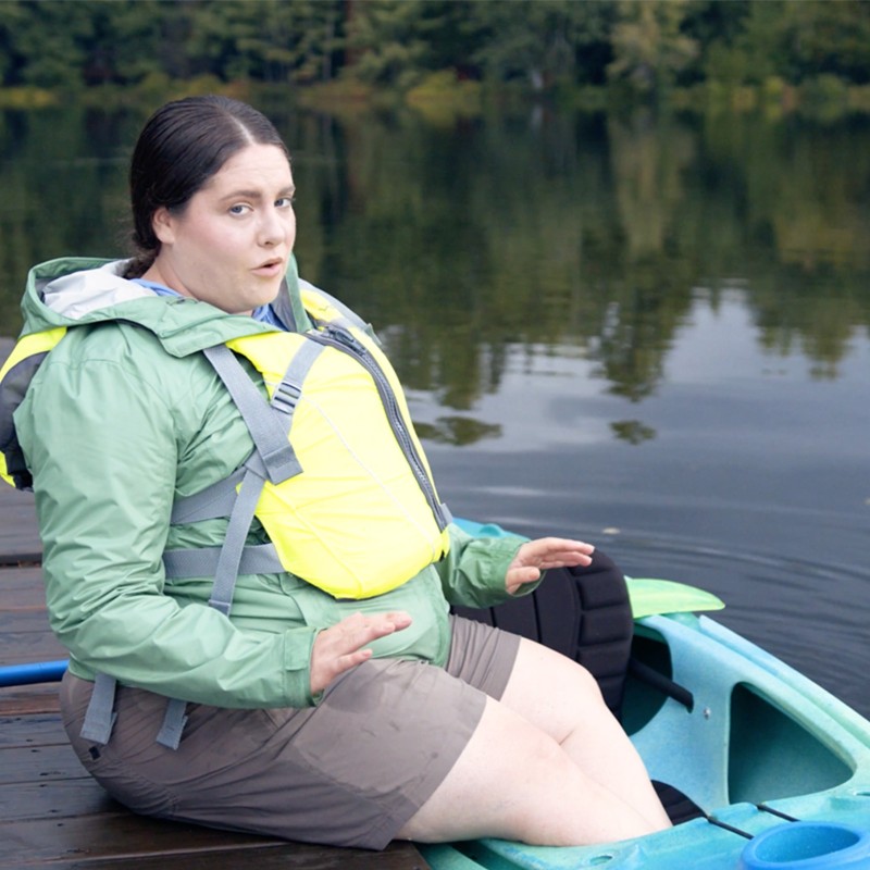 MacKenzie, sitting on a dock with both feet in a kayak.