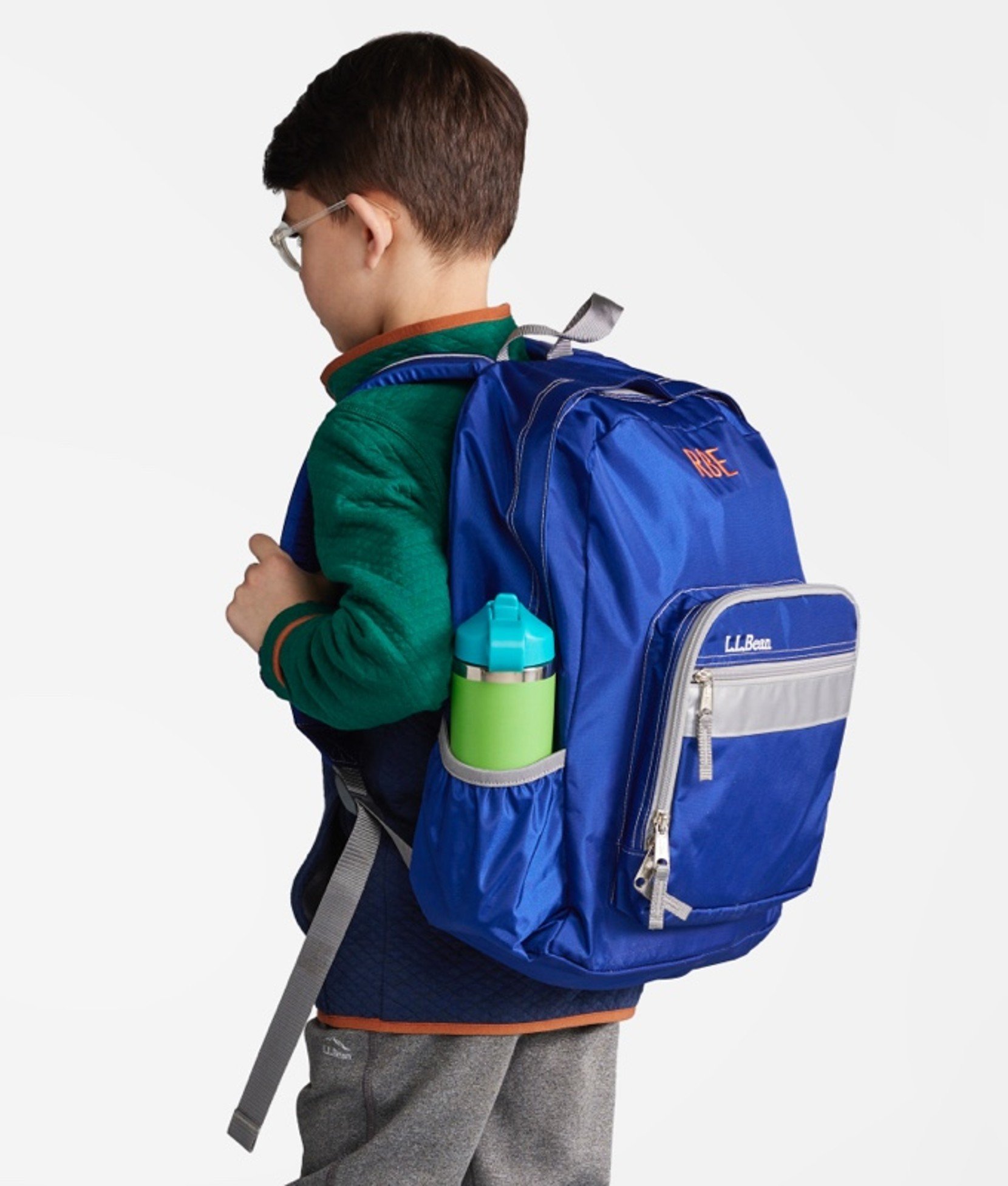 A young boy wearing a school backpack turned away from the camera so the backpack is shown at 3/4 view.