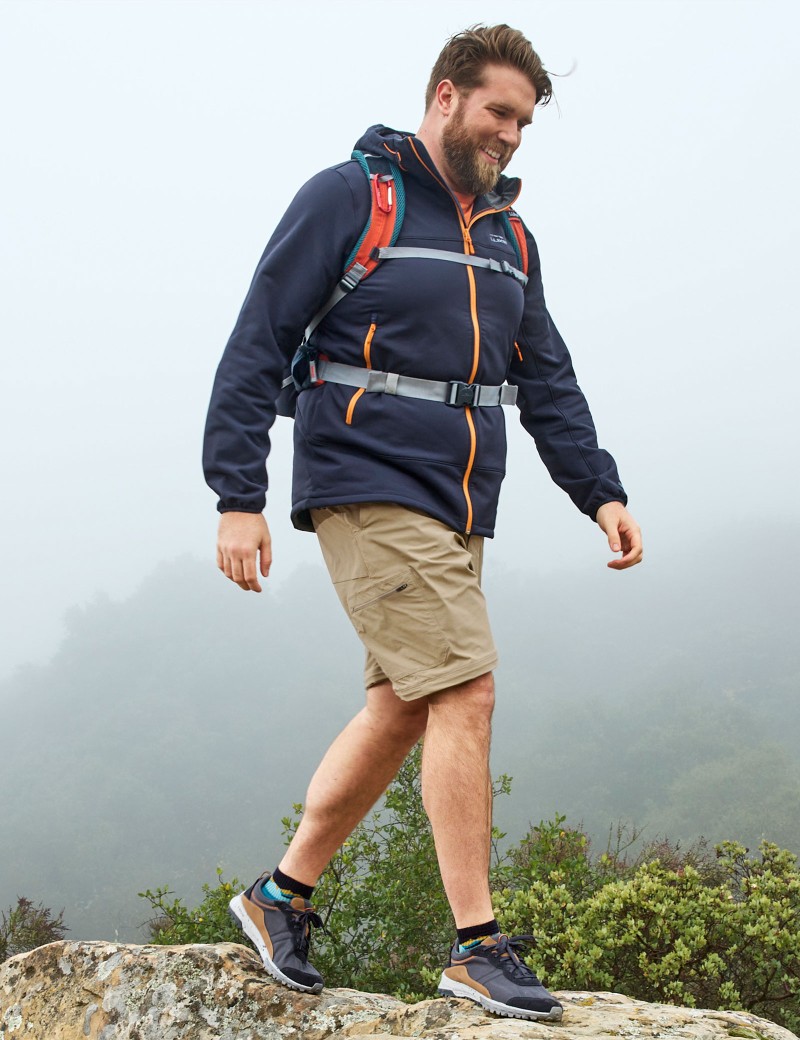 Man walking on rocky trail wearing a day pack.