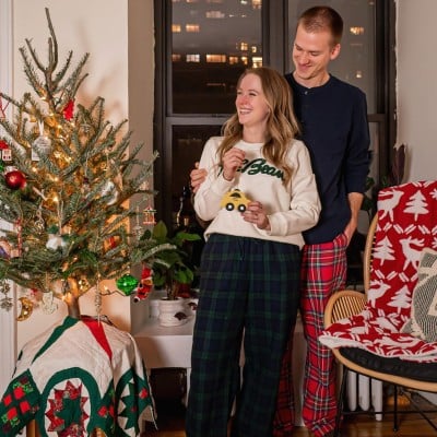 A smiling couple in L.L.Bean pajamas standing by a holiday tree.
