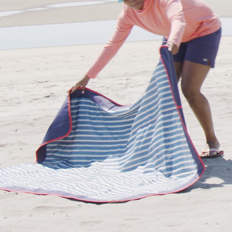 Stephanie spreading out a beach blanket on the sand.