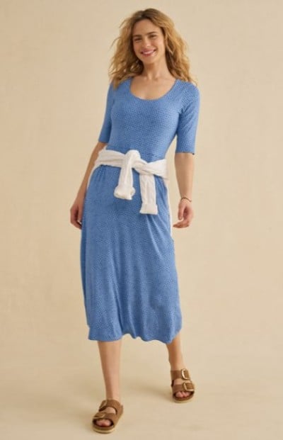 Blue midi dress with half‑length sleeves, a white sweater tied at the waist, and sandals.