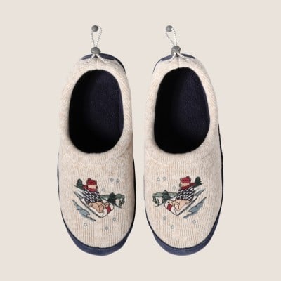 Cream slippers with fleece lining and sledding bear embroidered on top.