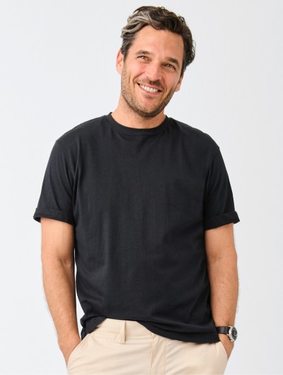 A thigh-up shot of a man wearing a black t-shirt.