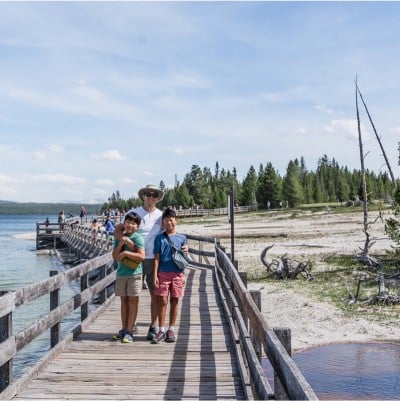 An adult and two kids standing on a dock on a beautiful summer day.