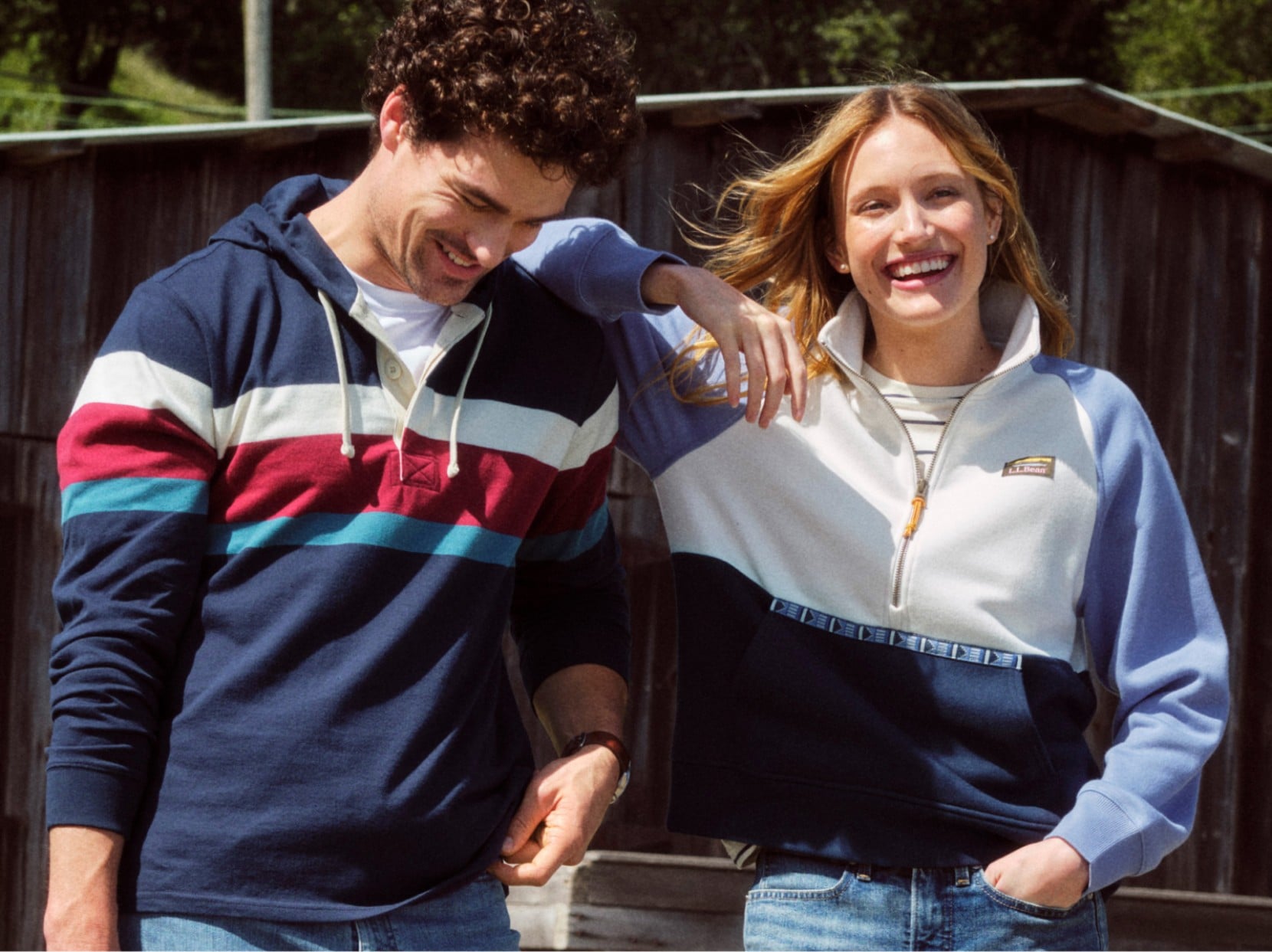 Two people standing outdoors wearing casual striped and color-block pullovers.
