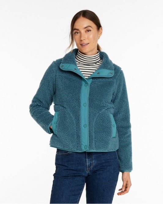Woman wearing a teal fleece jacket with button details and striped shirt underneath.