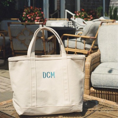 A monogrammed canvas tote bag on a patio table.