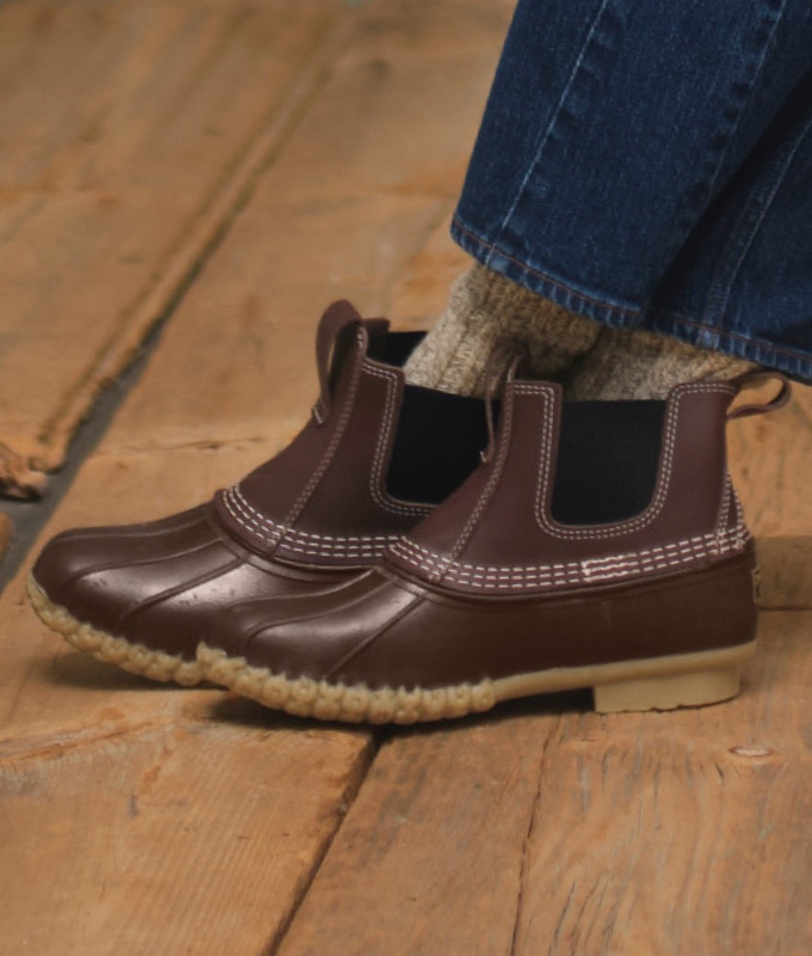 Close up of brown slip-on duck boots with wool socks and cuffed jeans. 