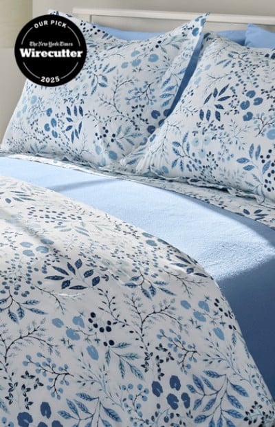 A neatly folded bed with matching blue and white floral bed sheets and pillows. Wirecutter top pick badge.