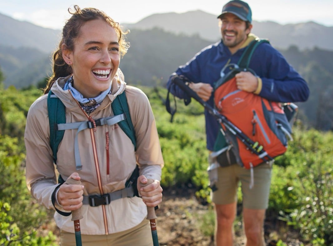 Smiling woman and man hiking in L.L.Bean clothing.