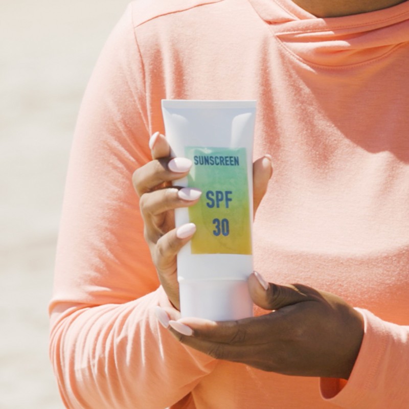 Close-up of hands holding a tube of SPF 30 sunscreen.