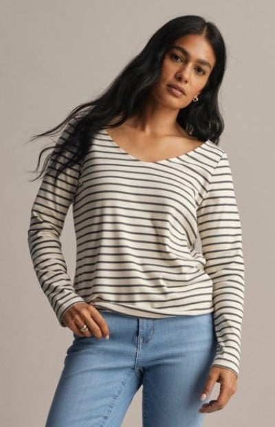 Person wearing a cream and navy striped long-sleeve shirt with light blue jeans.