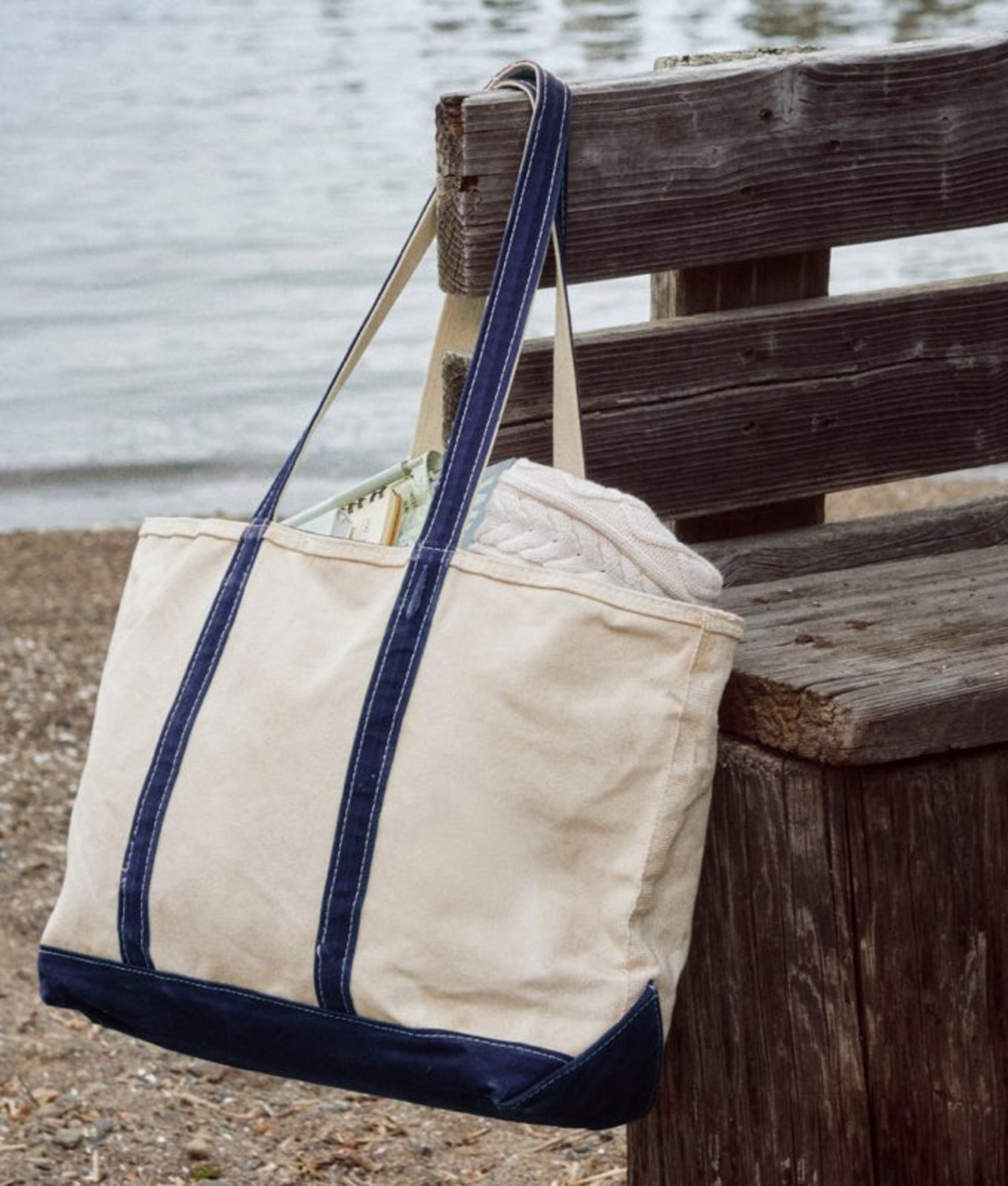 Canvas tote bag hanging on weathered wooden railing, labeled totes