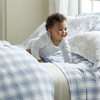 Smiling baby on bed with flannel sheets