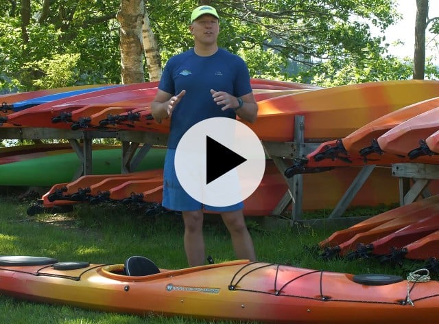 Kayak instructor standing in front of kayaks.