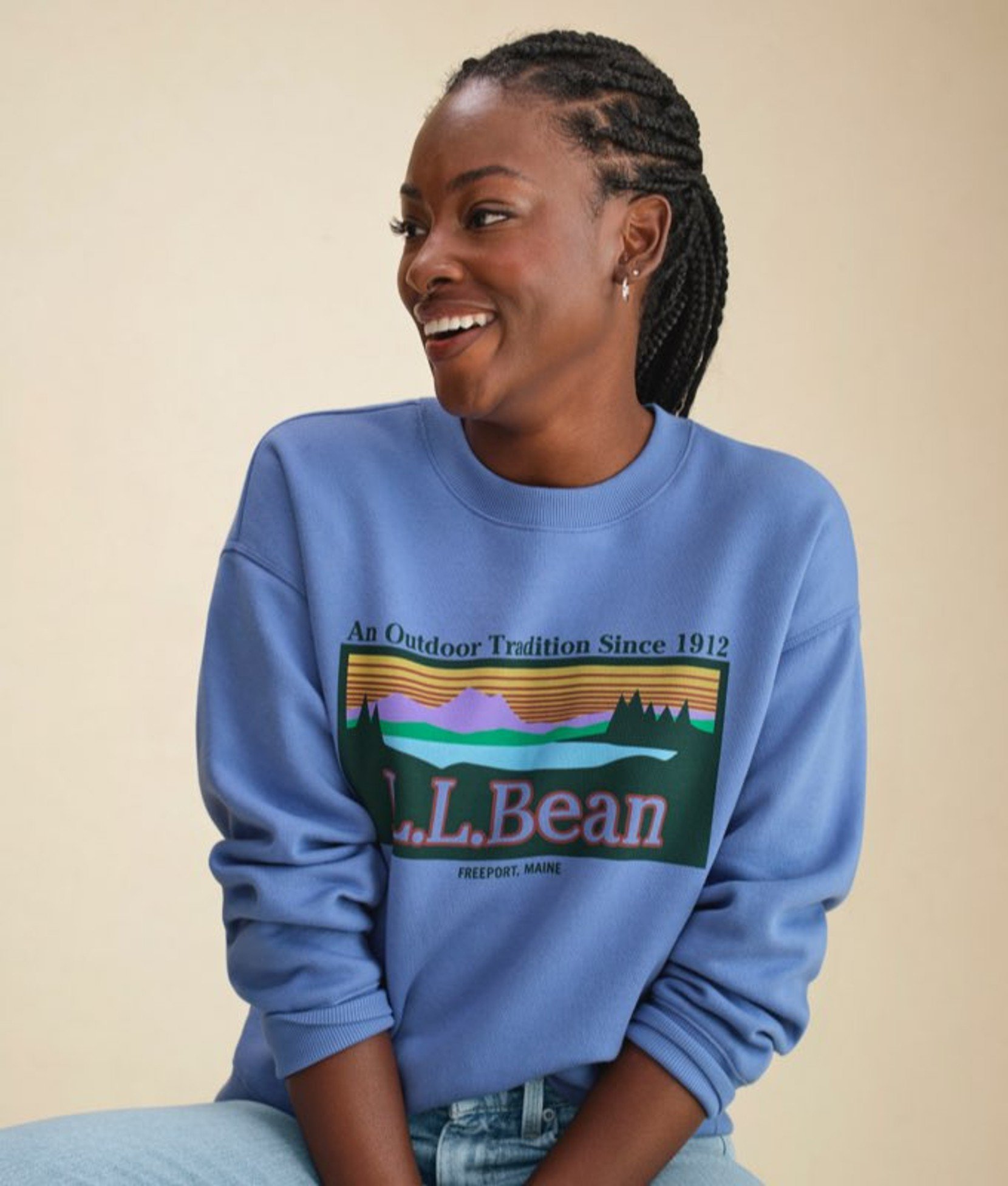 Woman wearing a lavender sweatshirt with L L Bean mountain logo graphic.
