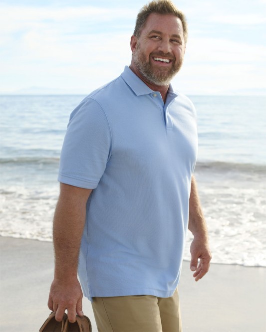 A man walking on the beach wearing a light blue Double L Polo.