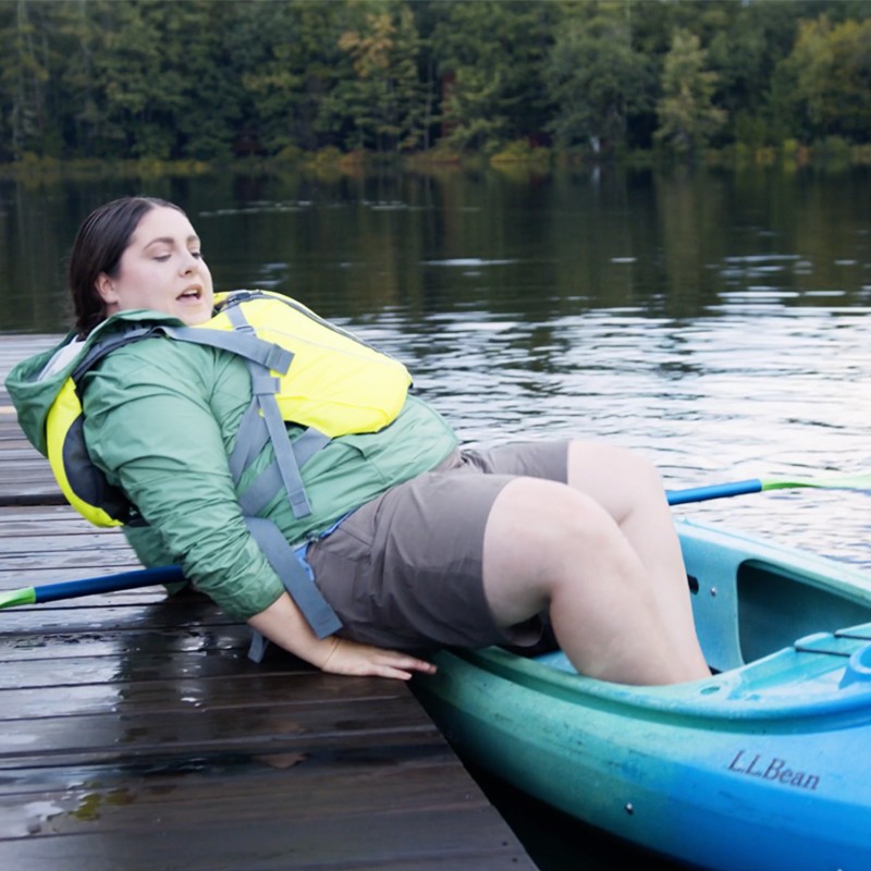 MacKenzie lifting herself onto a dock from a kayak.