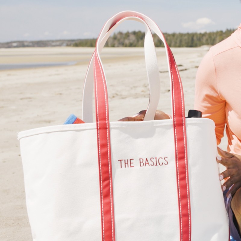 Close-up of a Boat & Tote on the beach with "The Basics" embroidered on it.