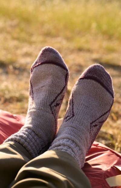 Feet in gray socks resting on a blanket in a grassy outdoor setting.