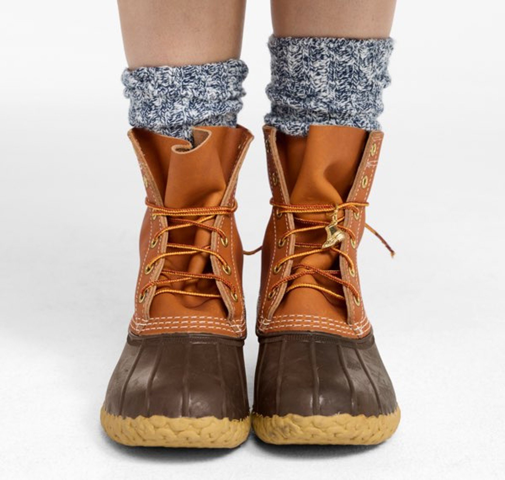 Person wearing tan lace-up rain boots with patterned socks visible above.